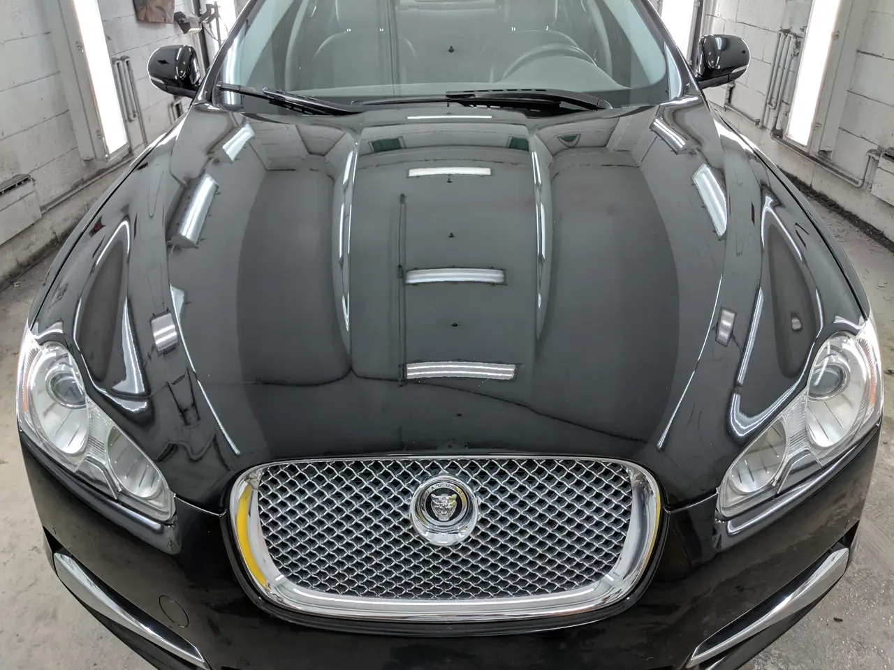 Capot et calandre chromée d’une Jaguar noire dans l’atelier