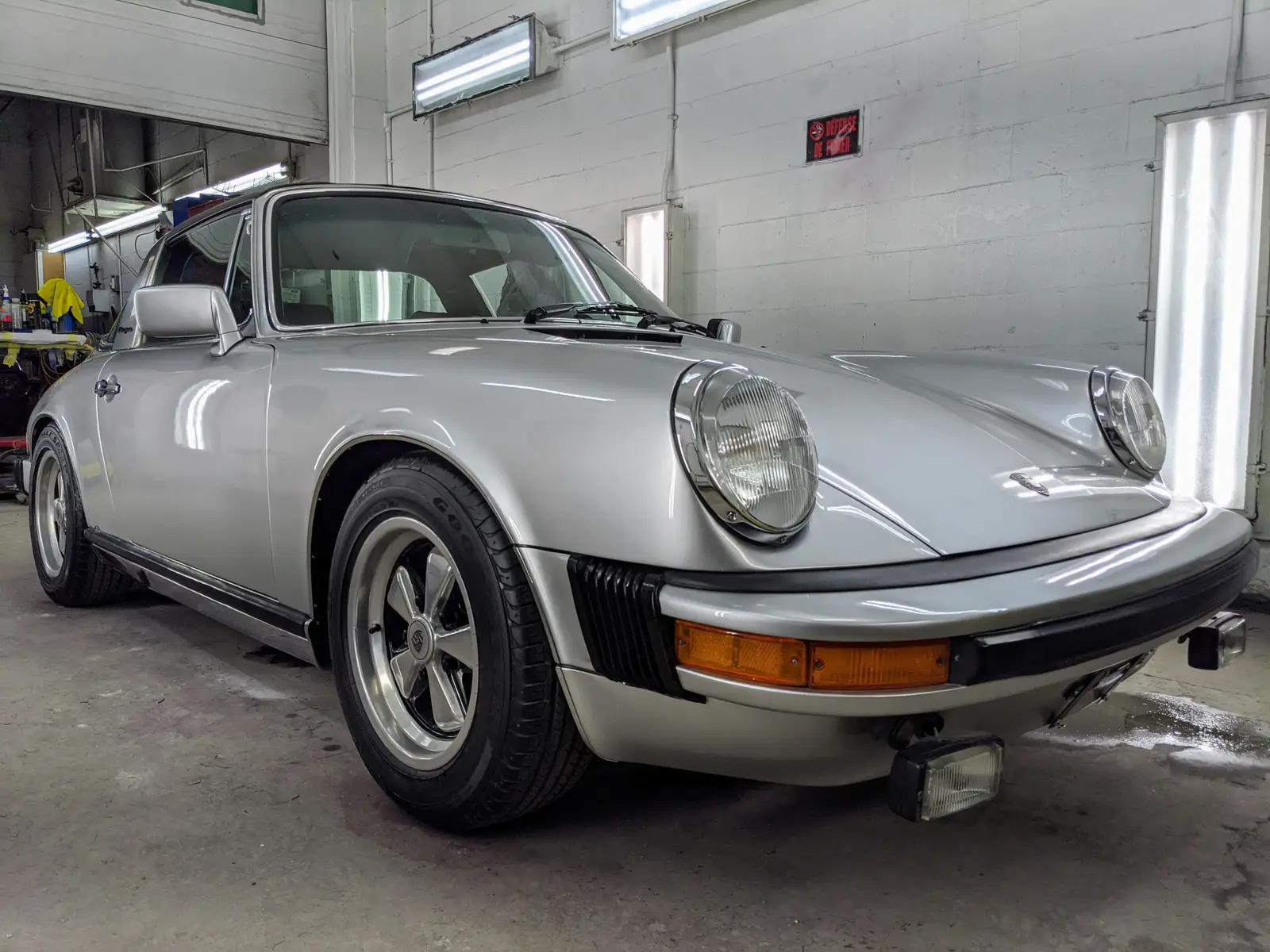Porsche 911 argentée dans l’atelier de carrosserie SLM Auto