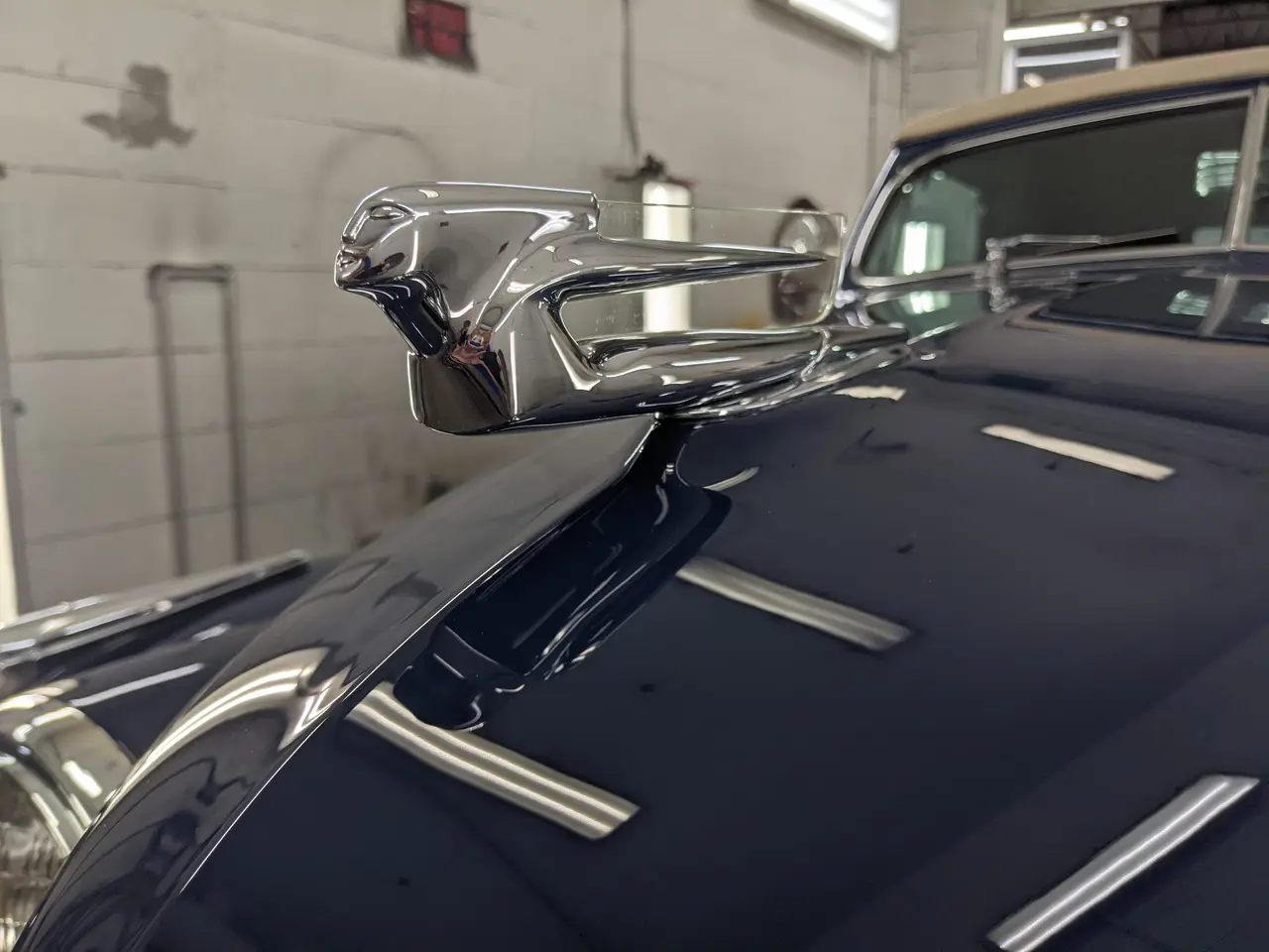 Ornement de capot chromé sur une voiture classique bleu marine au toit beige